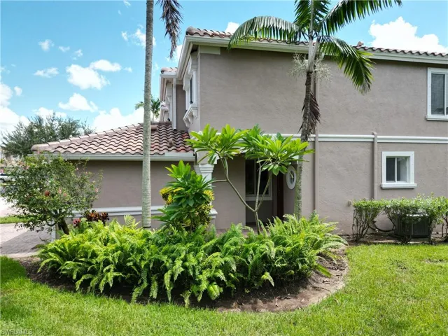View of side of property featuring stucco siding, a lawn, and a tiled roof