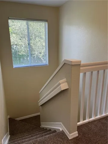 Stairway featuring a textured wall and carpet floors