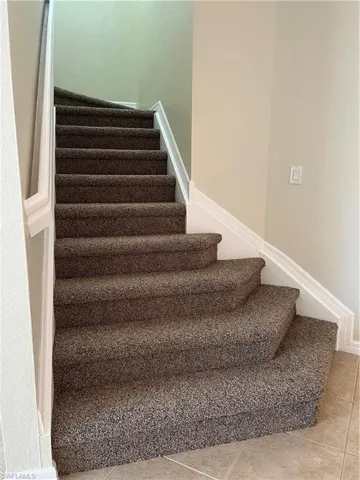 Stairway featuring tile patterned flooring and a textured wall