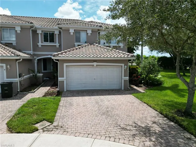 Mediterranean / spanish house with stucco siding, decorative driveway, a front lawn, an attached garage, and a tile roof