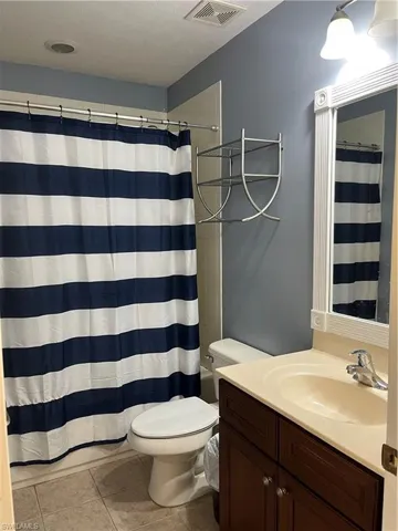Full bathroom featuring a textured ceiling, vanity, light tile patterned floors, and shower / bath combination with curtain