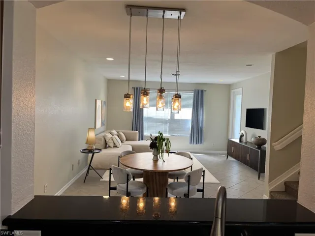 Dining room with light tile patterned floors, stairs, and a textured wall