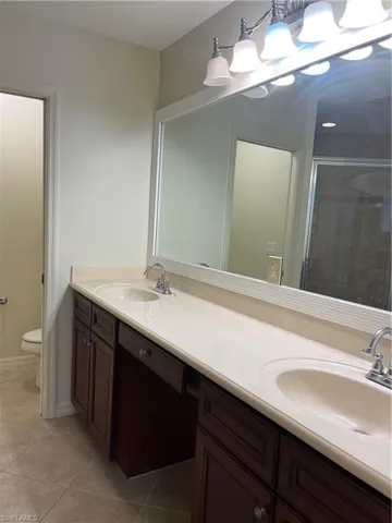 Bathroom with double vanity, a stall shower, and light tile patterned flooring
