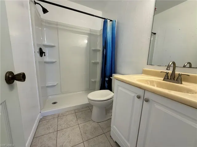 Full bathroom with a stall shower, vanity, and light tile patterned floors