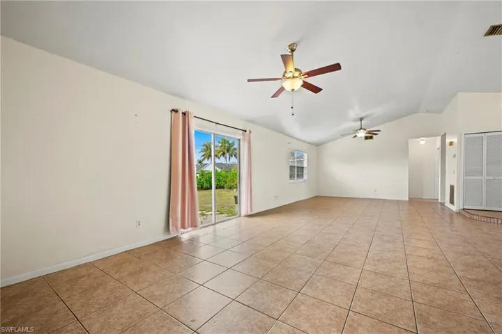 Unfurnished room featuring vaulted ceiling, ceiling fan, and light tile patterned floors