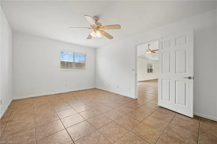 Empty room with a ceiling fan and light tile patterned flooring