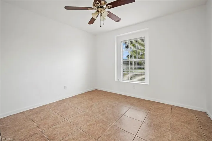 Empty room with light tile patterned flooring and a ceiling fan