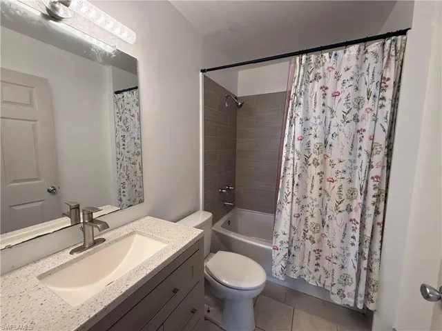 Bathroom with vanity, shower / bath combo, and light tile patterned flooring