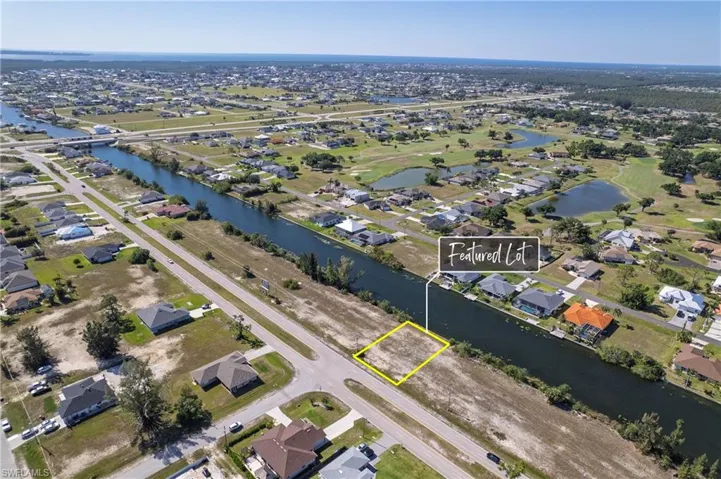 Aerial view of property and surrounding area featuring nearby suburban area, a large body of water, and property boundaries highlighted