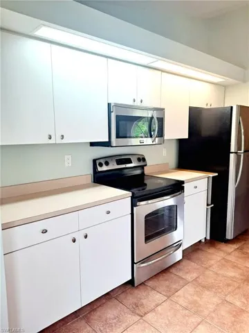 Kitchen with appliances with stainless steel finishes, white cabinetry, light countertops, and light tile patterned floors
