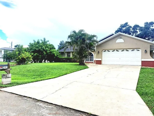 Ranch-style house with stucco siding, an attached garage, concrete driveway, and a front yard