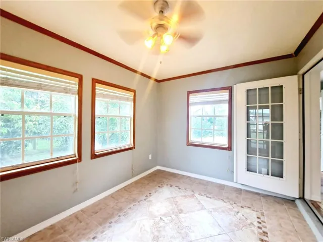 Unfurnished room featuring crown molding, a ceiling fan, and light tile patterned flooring