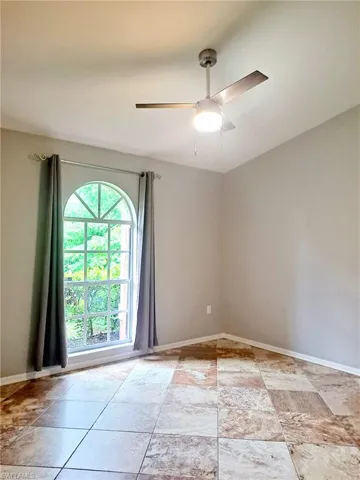 Unfurnished room with ceiling fan and baseboards