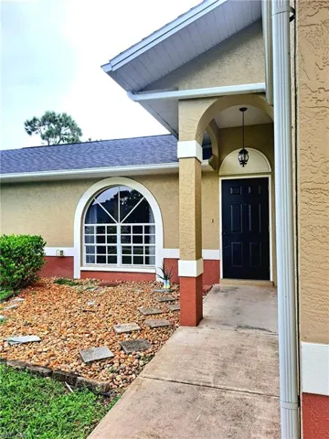 Entrance to property featuring stucco siding and roof with shingles