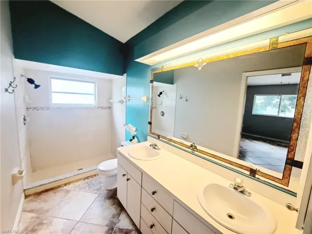 Bathroom featuring a stall shower, double vanity, healthy amount of natural light, and light tile patterned floors