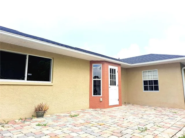 Property entrance featuring stucco siding, a patio area, and a shingled roof