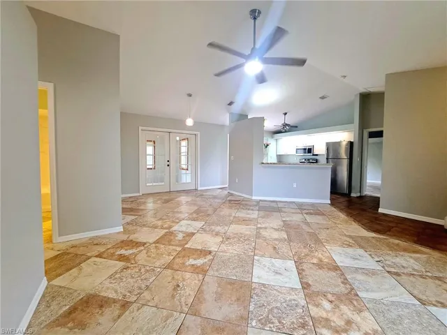 Unfurnished living room with french doors, lofted ceiling, and a ceiling fan