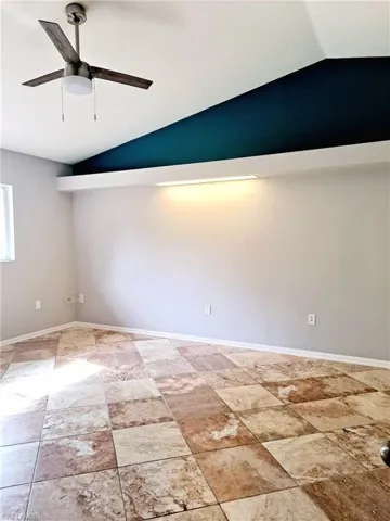 Unfurnished room featuring lofted ceiling and a ceiling fan