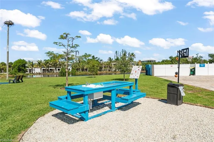 Outdoor space featuring a gravel surface, built-in wash station table, basketball hoop, and manicured lawn area