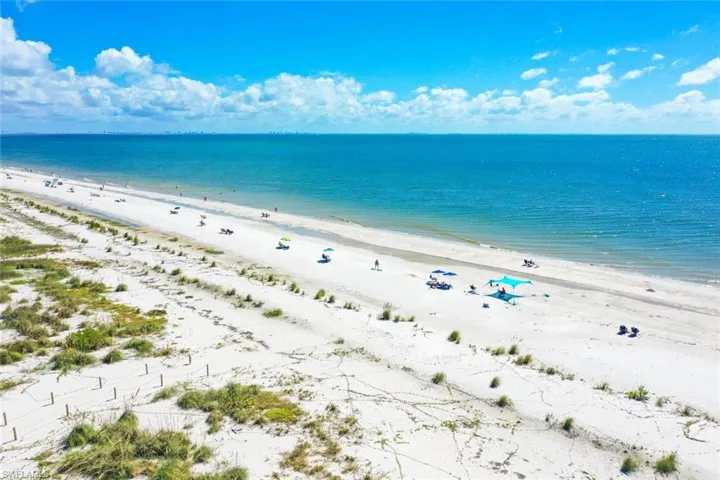 Direct waterfront access featuring a white sand beach, native dune vegetation, and wooden post fencing