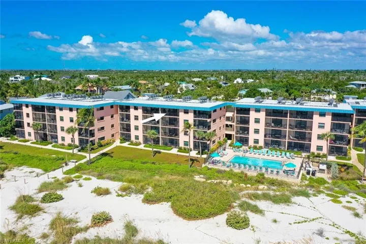 Beachfront residential complex featuring direct sand access, a swimming pool, and private balconies