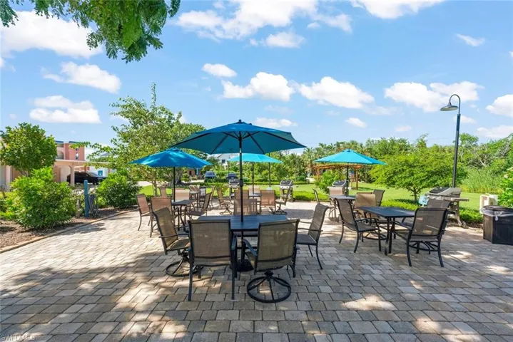 Expansive paver patio featuring built-in charcoal grills, perimeter landscaping, and a dedicated lamp post