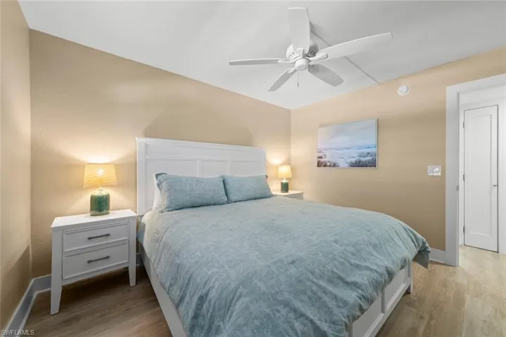 Room featuring wood-finish flooring, a white ceiling fan, and a neutral color palette