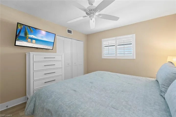 Room featuring a ceiling fan with integrated lighting, dual-panel closet doors, and plantation shutters