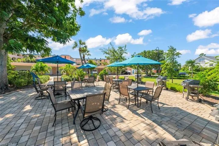 Paver patio featuring integrated grills and mature landscaping