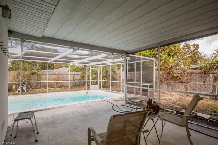 View of pool with a sunroom, glass enclosure, a fenced backyard, and patio surround