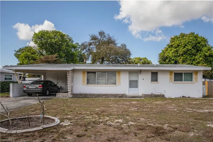 View of front of home with a carport, a front lawn, and driveway