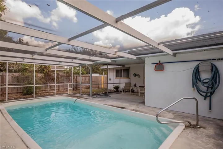 View of pool with glass enclosure, a fenced backyard, patio surround, and a sunroom