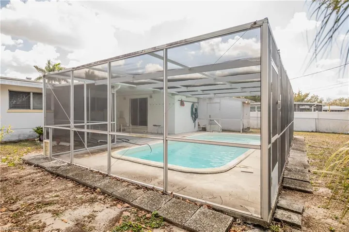 Back of property with a sunroom, an outdoor pool, a fenced backyard, glass enclosure, and a patio