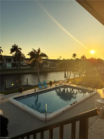 Pool at dusk sunsetting with a water view, and a community pool.