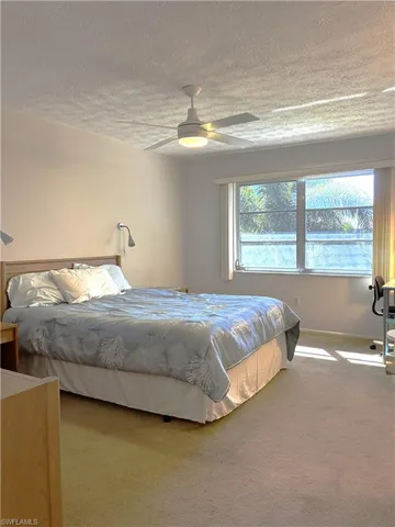 Carpeted bedroom featuring a ceiling fan and a textured ceiling
