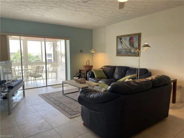 Spacious and furnished tiled living room with views to outside treetops and waterway