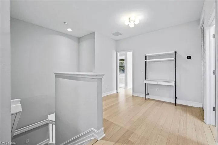 Hall with an upstairs landing, light wood-style floors, and recessed lighting