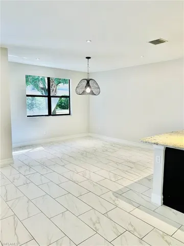 Unfurnished dining area with light marble finish floors and a chandelier