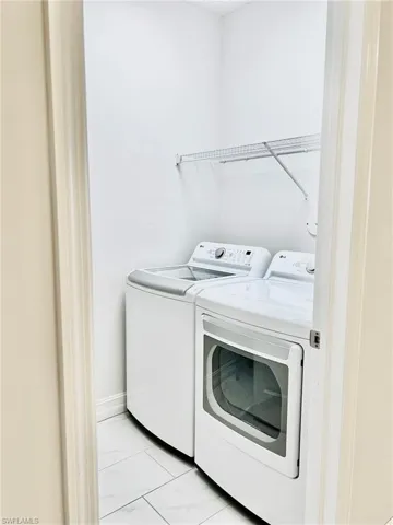 Laundry room with washer and dryer and light marble finish floors