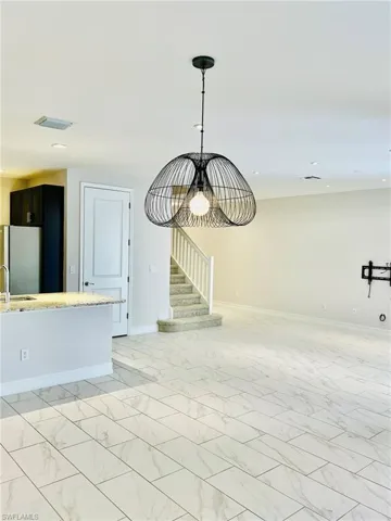 Unfurnished living room with hanging lights and light marble finish floors