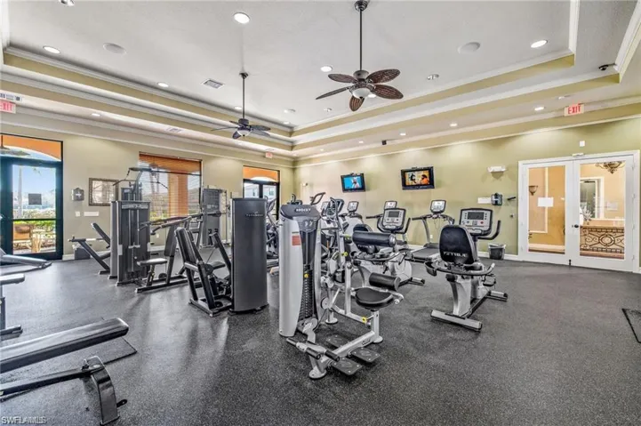 Workout area featuring a tray ceiling, ornamental molding, ceiling fan, and recessed lighting