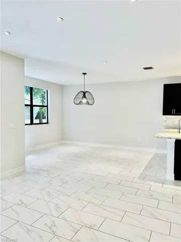 Unfurnished dining area with hanging lights and light marble finish floors