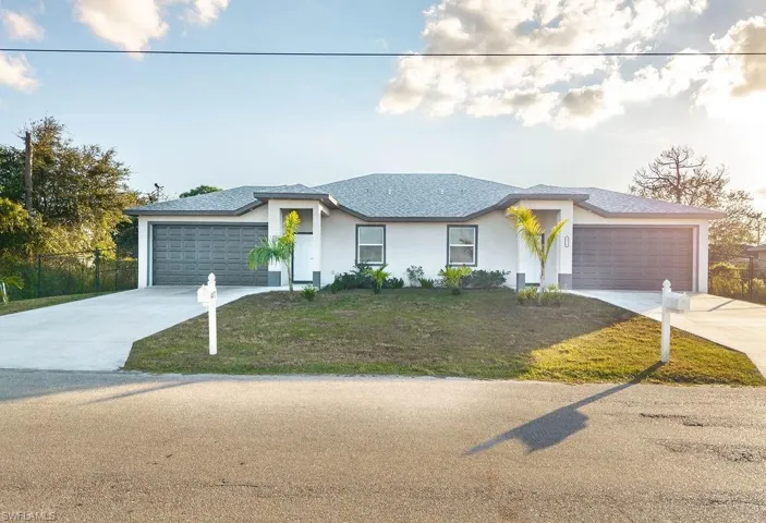 View of front facade with stucco siding, driveway, and an attached garage