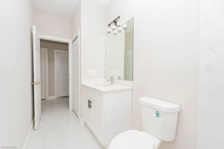 Half bathroom featuring light marble finish floors and vanity