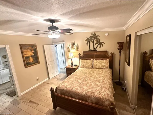 Primary Bedroom featuring ceiling fan, a textured ceiling, and ornamental molding