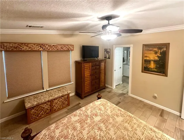 Primary Bedroom with a closet, ceiling fan, crown molding, and a textured ceiling