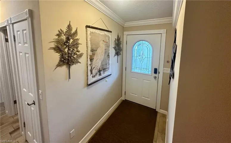 Doorway to outside featuring ornamental molding, wood-type flooring, and a textured ceiling