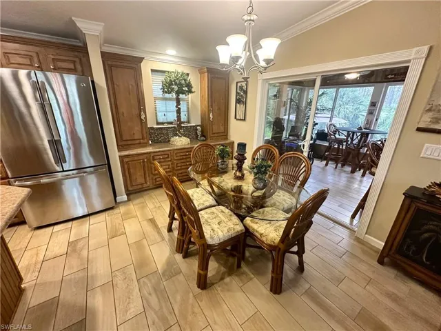 Dining space with crown molding, light hardwood / wood-style floors, and a chandelier
