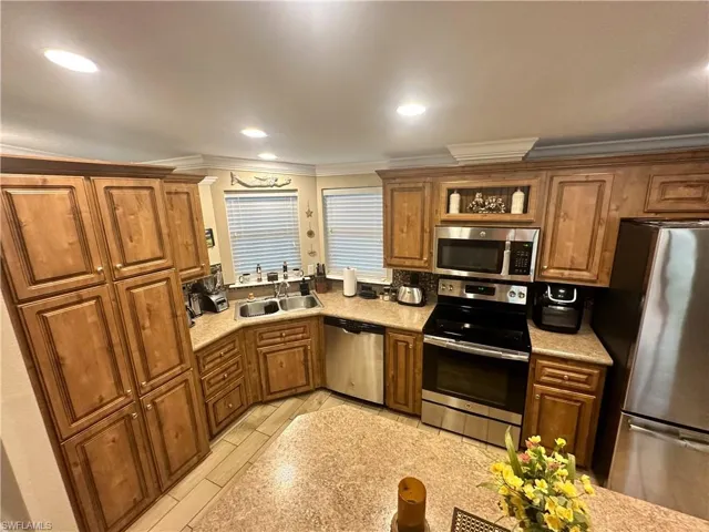 Kitchen with light wood-type flooring, appliances with stainless steel finishes, crown molding, and sink