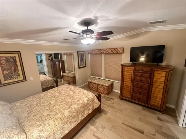 Primary Bedroom with a closet, ceiling fan, crown molding, and a textured ceiling
